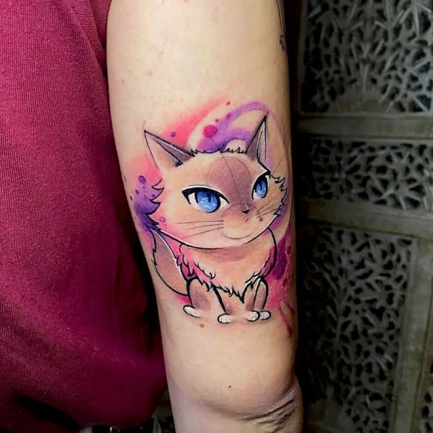 colorful cat with blue eyes tattoo on the arm