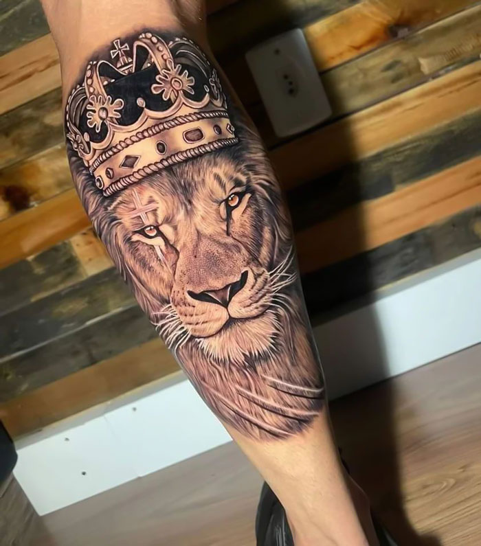 Lion tattoo with crown on a calf, showcasing detailed animal tattoo art.