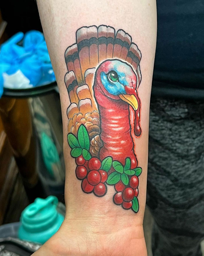 Colorful turkey animal tattoo design on forearm, featuring vibrant reds and greens.