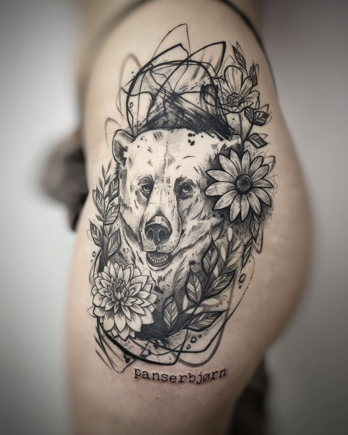 Realistic bear tattoo with floral accents on the arm, highlighting animal tattoo simplicity and realism.