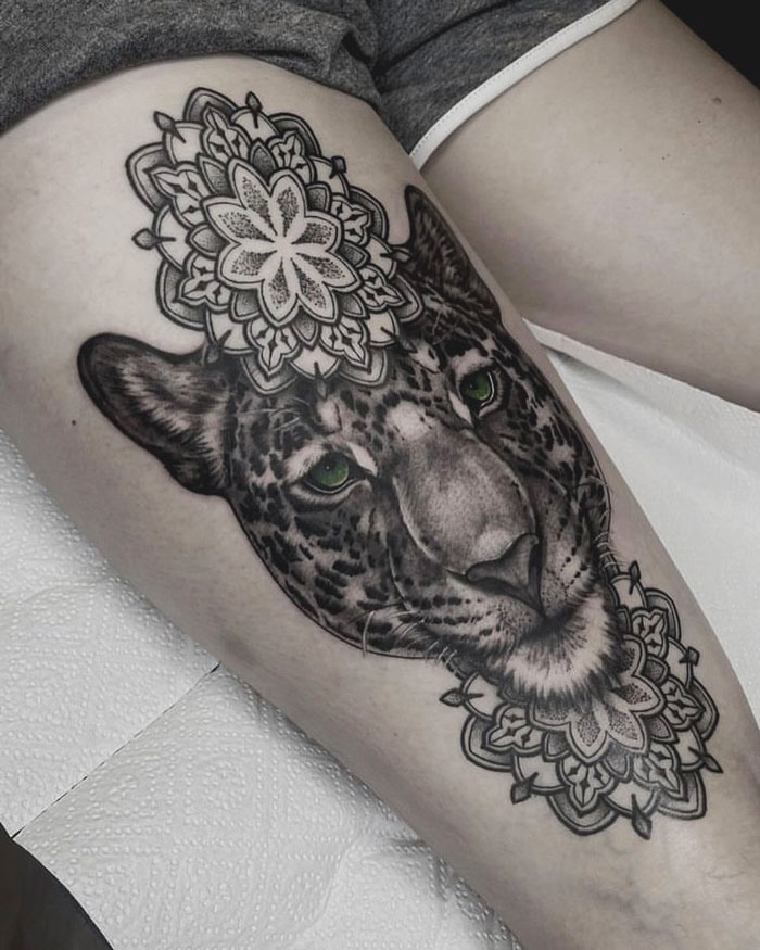 Tattoo of a leopard with mandala designs, showcasing intricate animal tattoo artistry on the leg.