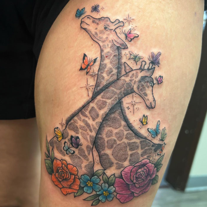 Two giraffes, butterflies and colorful flowers tattoo