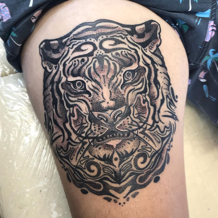 Black tiger face tattoo on leg