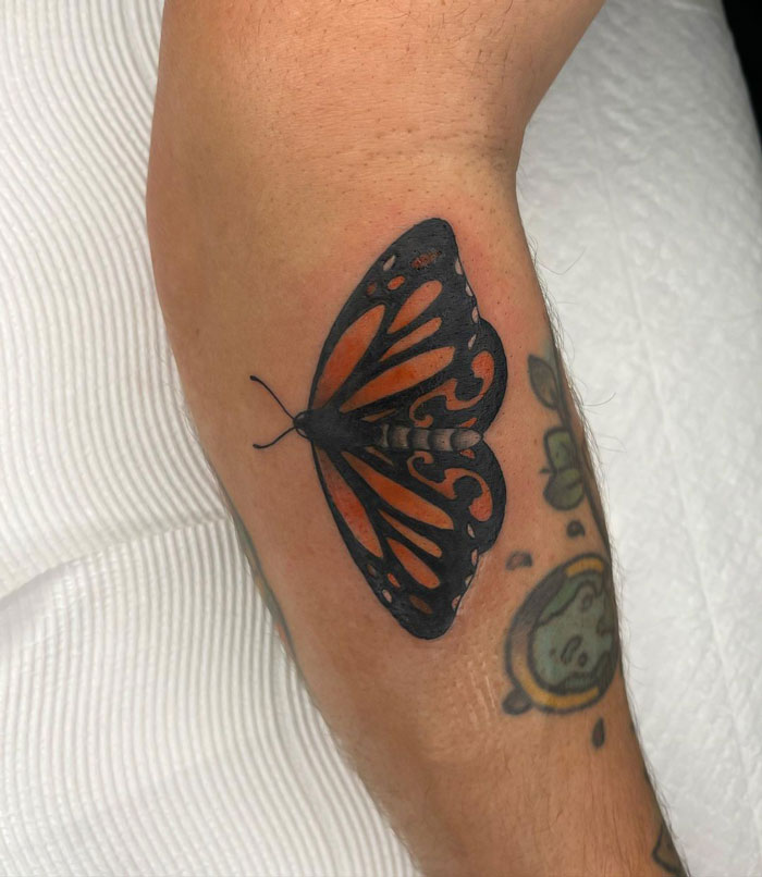 Butterfly animal tattoo on a forearm with vibrant orange and black details.