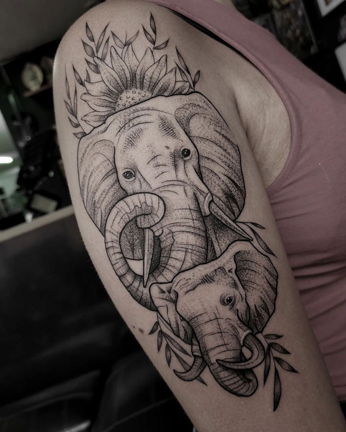 Two elephant faces and flower tattoo on arm