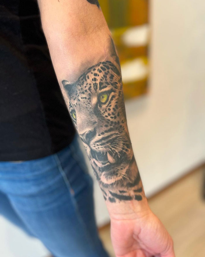 Realistic leopard tattoo on forearm, showcasing simplicity and lifelike animal art.