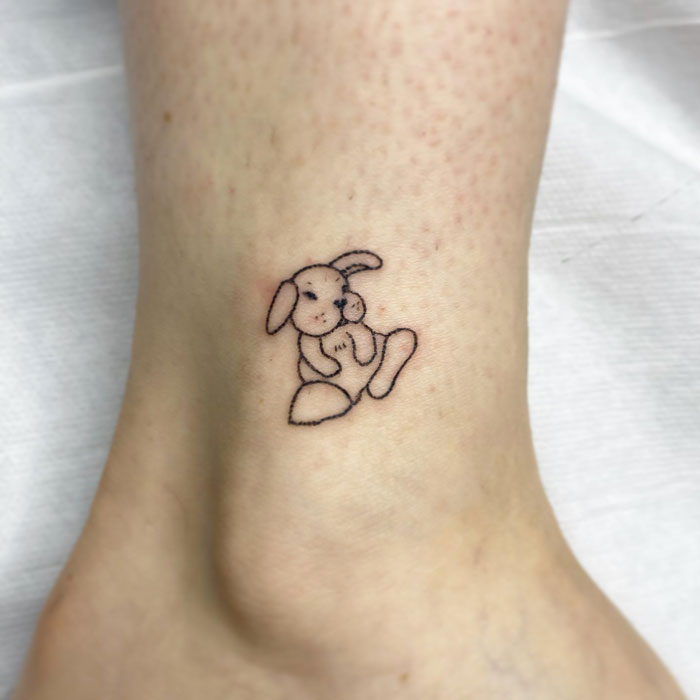 Little black linear bunny tattoo on leg