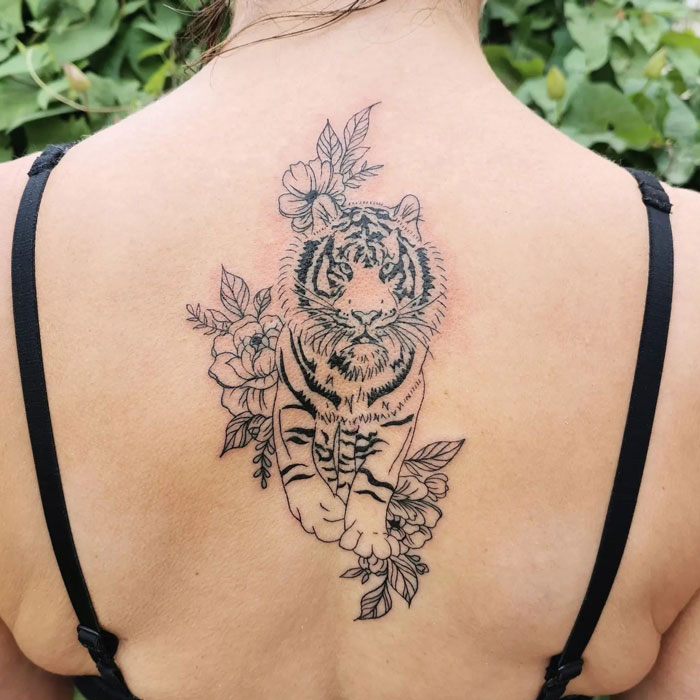 Tiger tattoo with floral design on back, illustrating animal tattoo inspiration.
