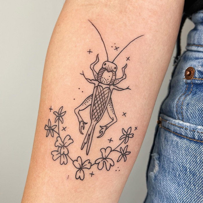 Animal tattoo of a detailed insect with floral elements on an arm.