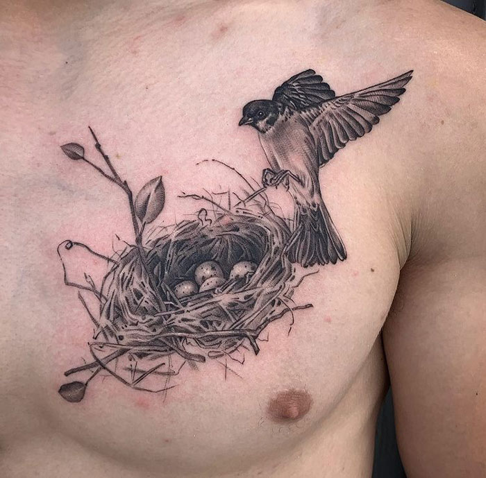 Bird tattoo with nest and eggs on chest, showcasing intricate animal tattoo design.