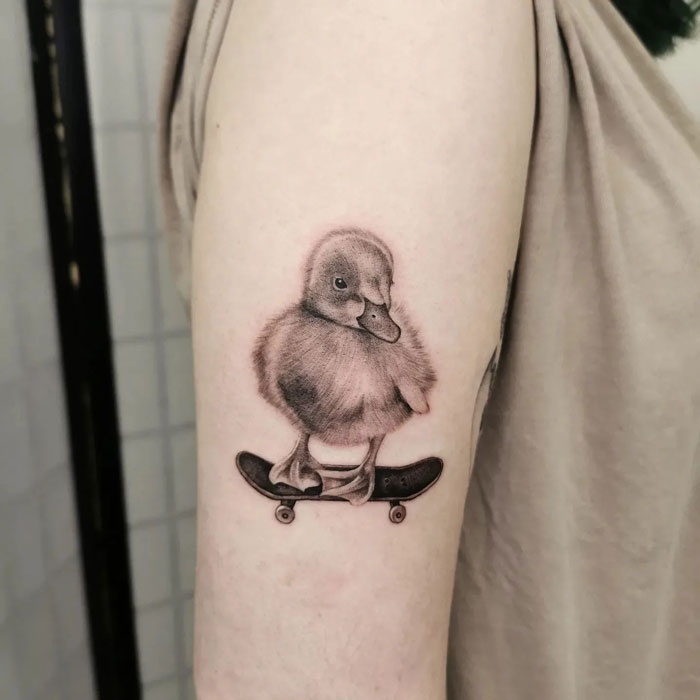 Realistic little duck on skateboard tattoo on arm