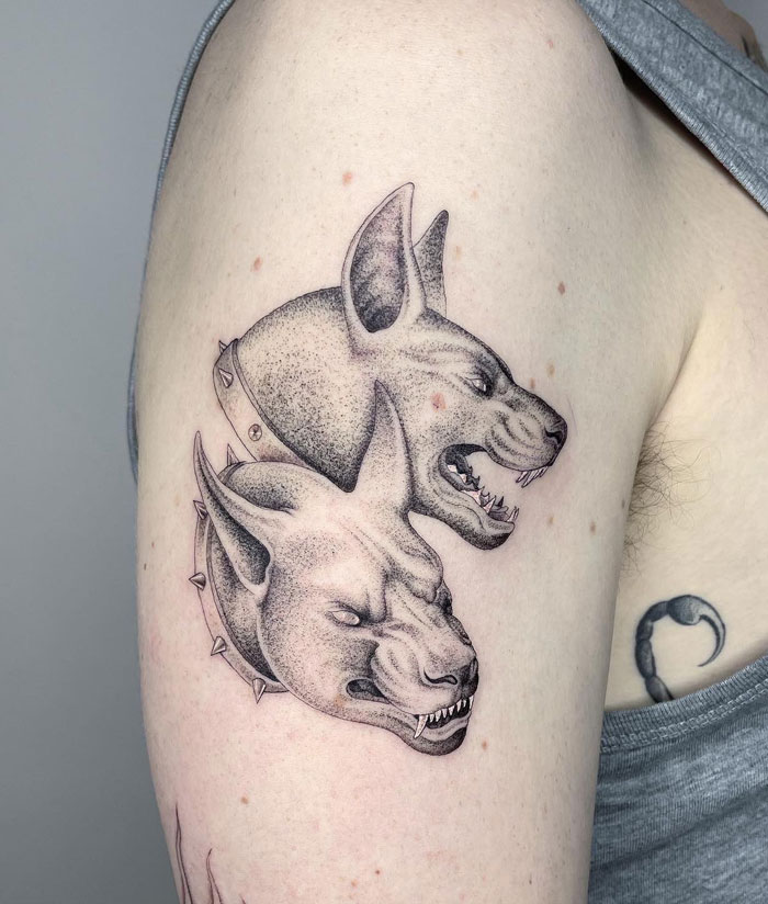 Two-headed mythical animal tattoo design on a person's upper arm.