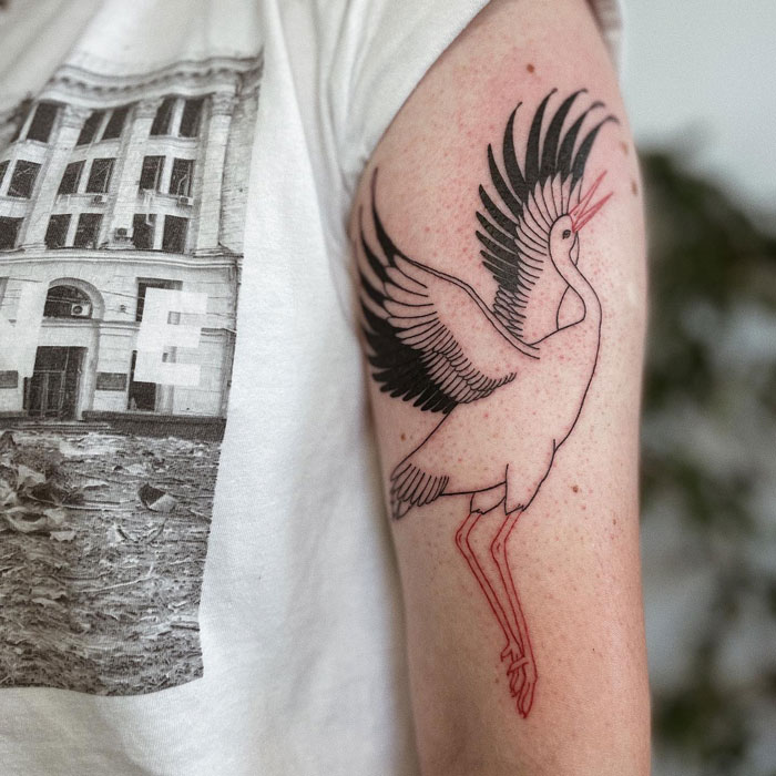 Arm with a bird tattoo featuring bold black and red lines, symbolizing one of many inspiring animal tattoo ideas.