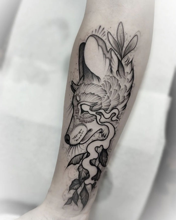 Animal tattoo design on forearm, featuring a stylized wolf with leaves and abstract patterns.