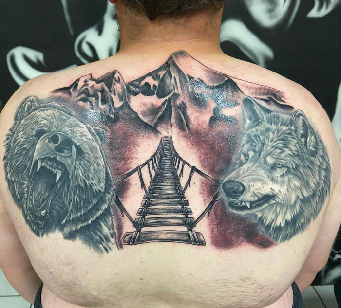 Bear, wolf mountains with bridge large tattoo on back