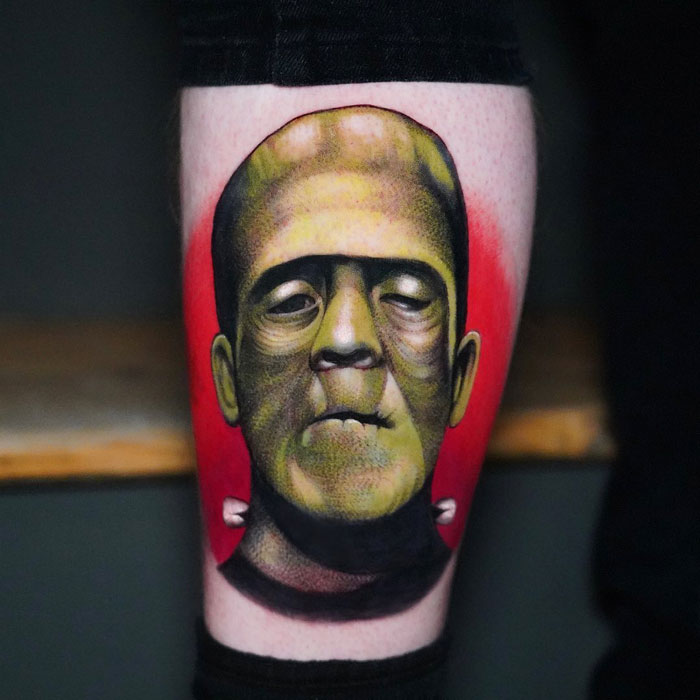 Unique calf tattoo featuring a vibrant Frankenstein's monster design against a bold red background.
