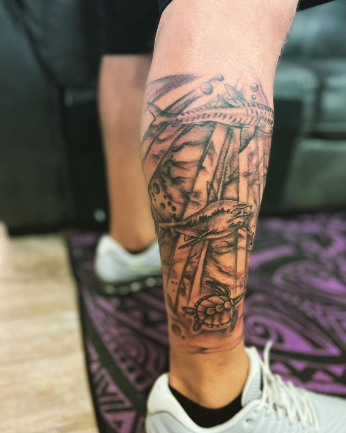 Unique calf tattoo featuring an underwater scene with a detailed shark and turtle design.