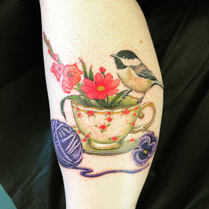 Watercolor tea cup with flower and bird in it calf tattoo