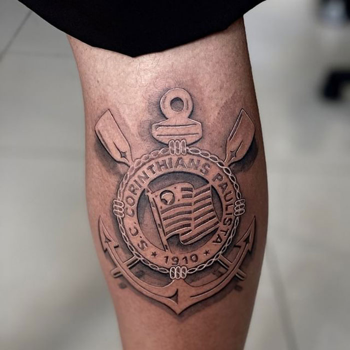 Unique calf tattoo featuring a detailed emblem with anchor and oars design.