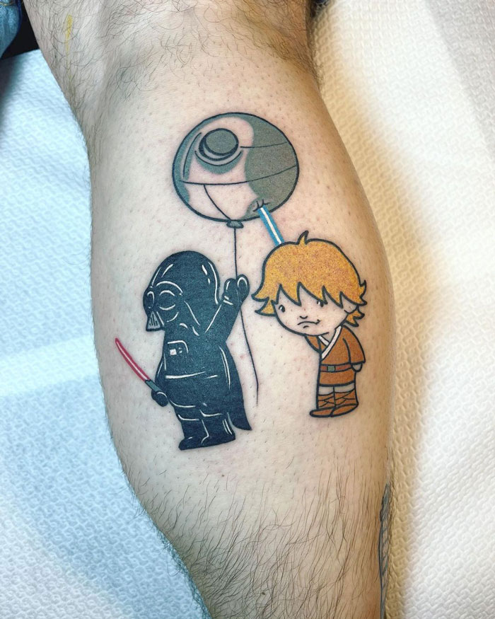Calf tattoo featuring cartoon-style characters, including a black figure with a balloon and a character in an orange outfit.