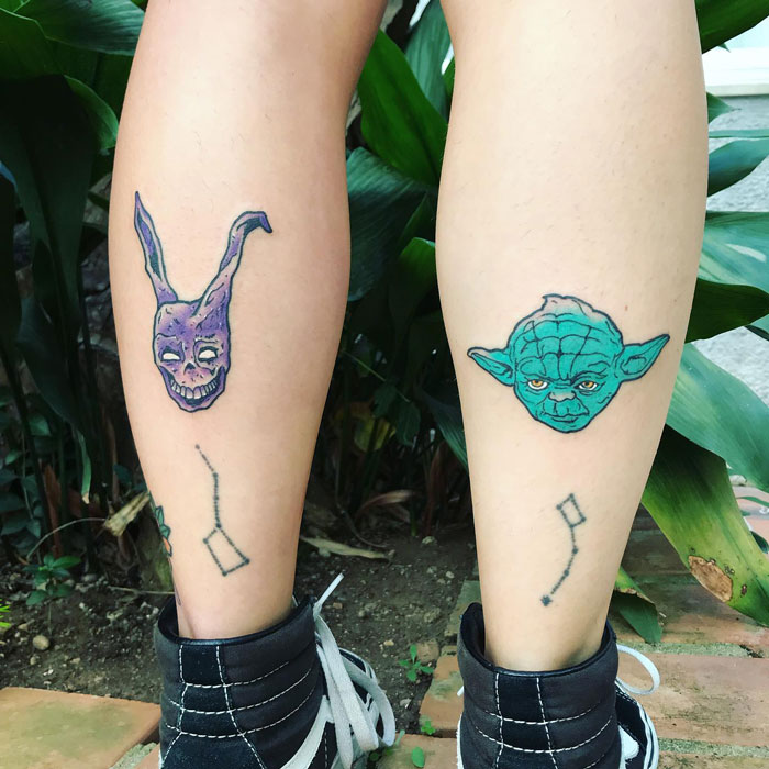 Unique calf tattoos featuring a purple rabbit skull and green creature, set against a leafy backdrop.