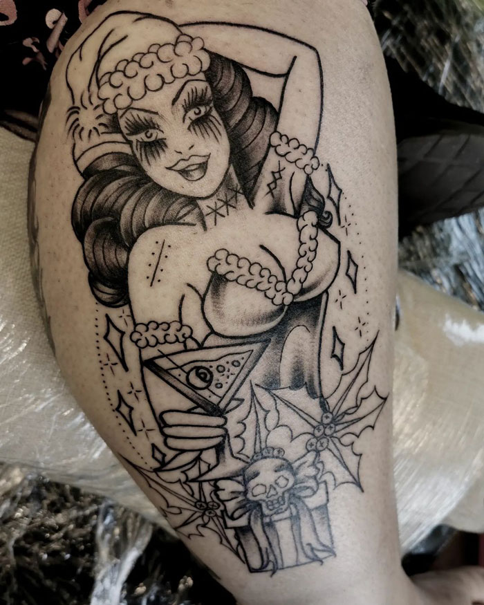 Unique calf tattoo featuring a retro pin-up style woman with festive details and a skull accent.
