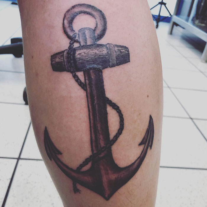 Anchor calf tattoo featuring detailed shading and rope design on a person's leg in a well-lit studio setting.