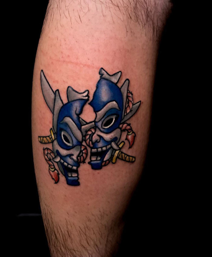 Blue mask calf tattoo design with sword accents, showcasing unique and cool tattoo ideas.