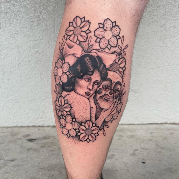 Calf tattoo featuring a woman with flowers and a comedy mask, showcasing unique tattoo design.