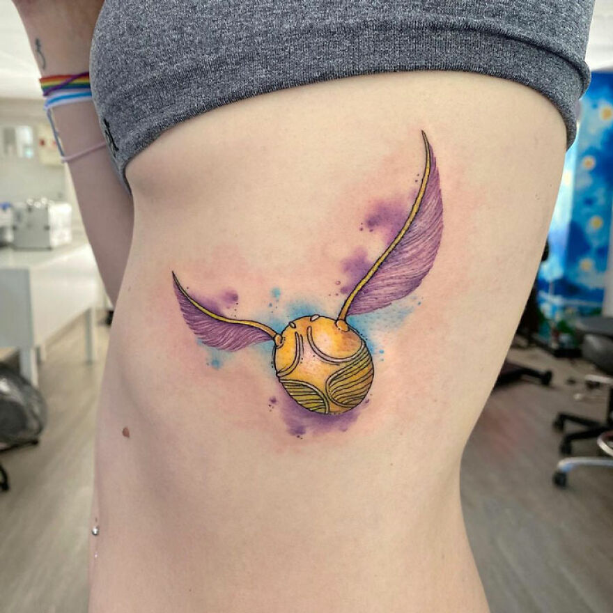 colorful golden snitch tattoo on the side