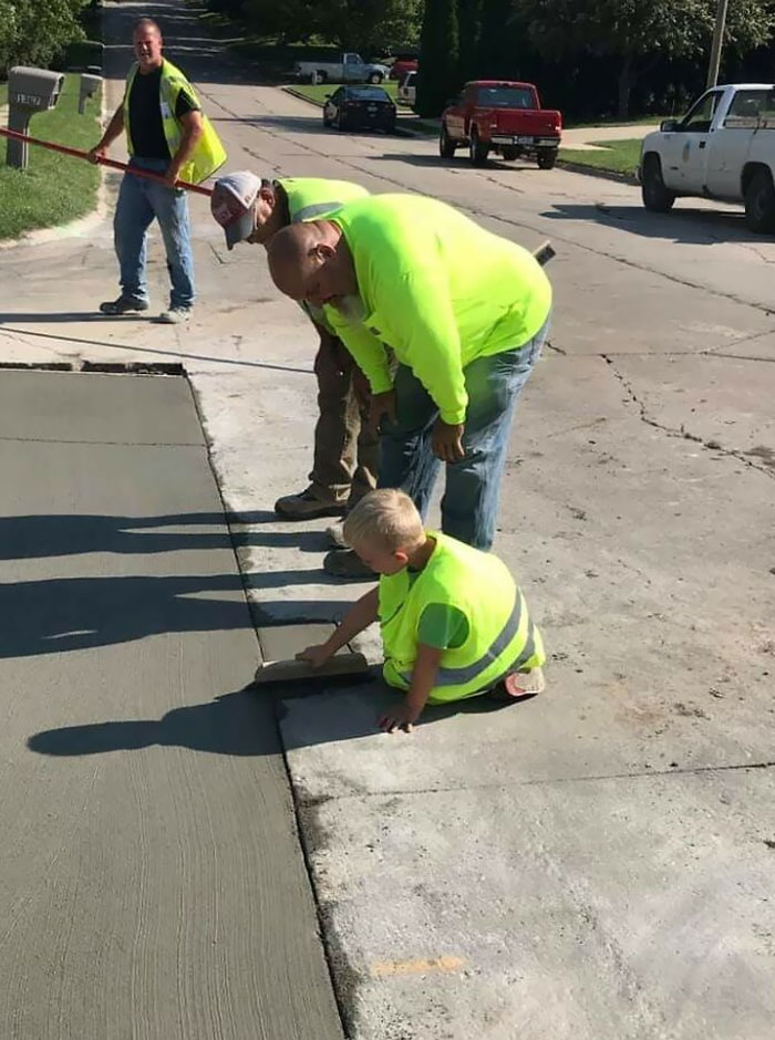 City Roads Crew Saw This Little Boy Sitting Outside With His Grandmother Wearing His Reflective Vest, And Watching Them Work. They Asked Him If He Wanted To Help