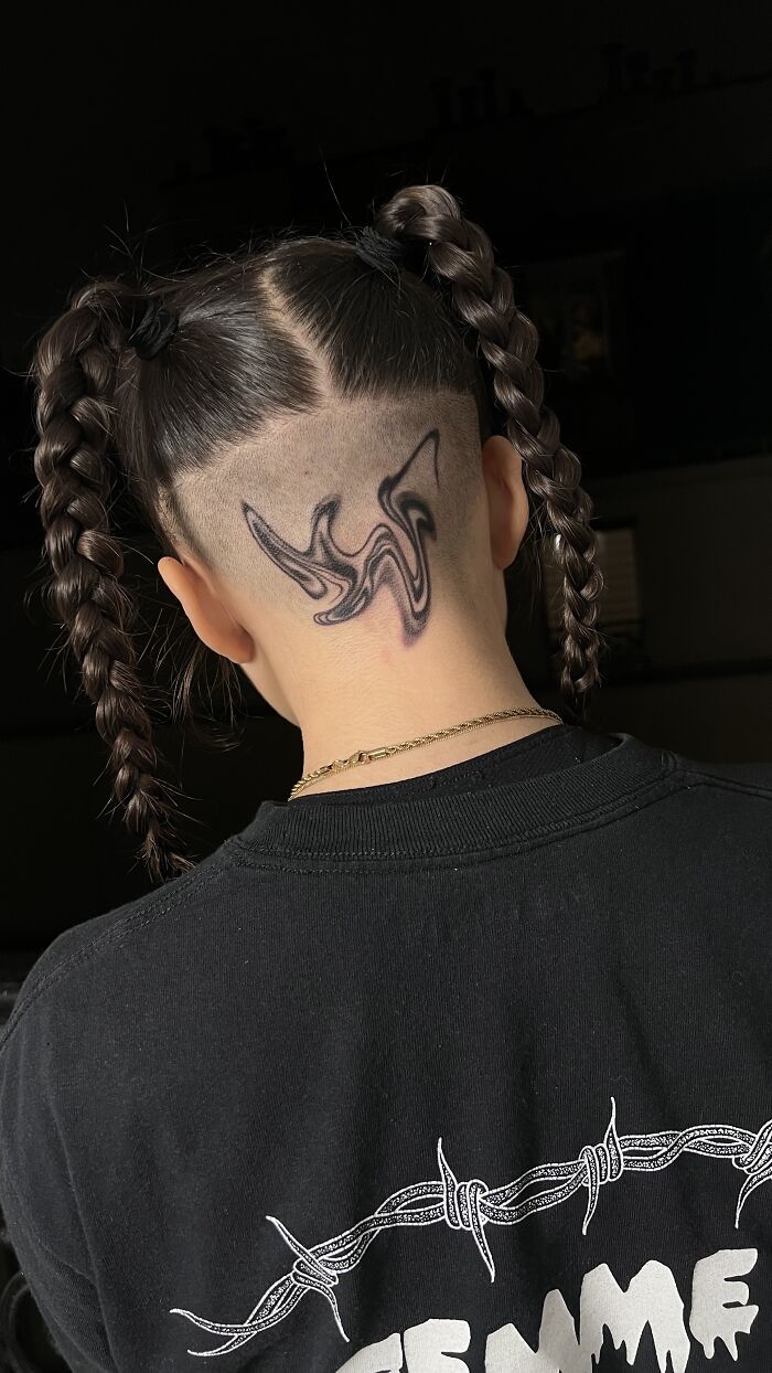 Under-hair tattoo design inspired by traditional marbling, person with braided hair.