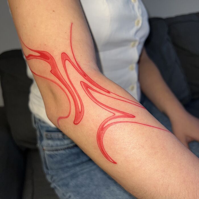 Tattoo design inspired by traditional Sernakkab marbling, featuring red flowing patterns on an arm.