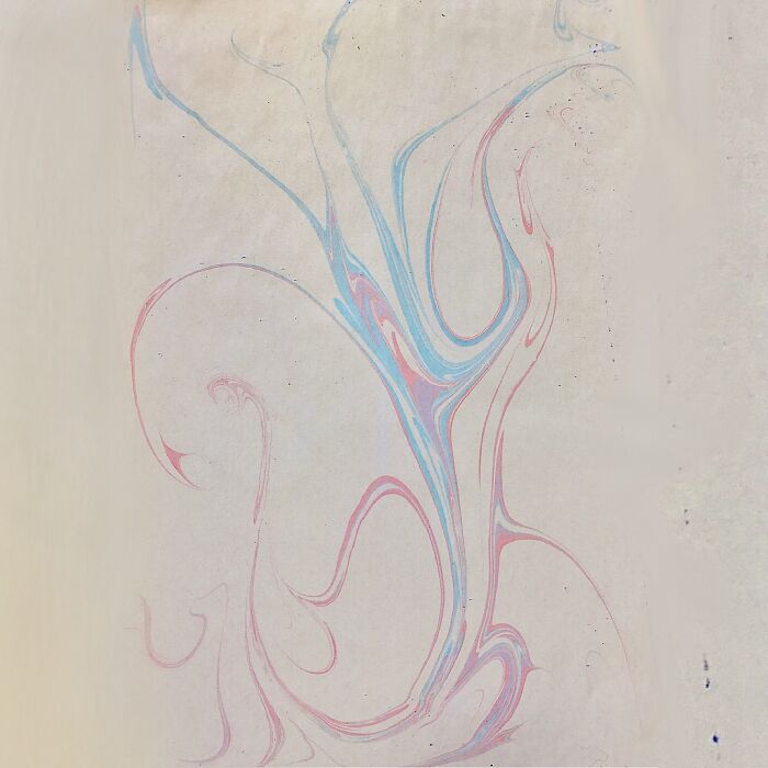 Abstract marbling design with blue and pink swirls forming a flowing pattern, reminiscent of traditional Sernakkab art.
