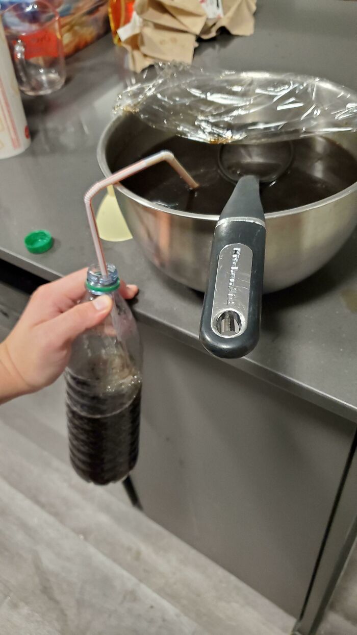 Pouring Coffee From My Bowl Of Coffee Into My Water Bottle With A Small Opening Using A Makeshift Siphon Made Out Of 2 Straws