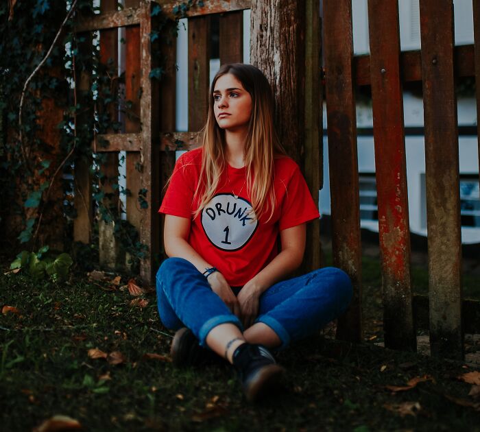 Woman In Red T-shirts Sitting Next To The Fence 
