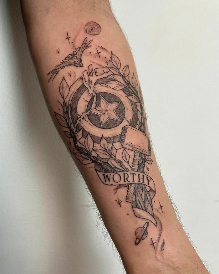Marvel tattoo featuring Captain America's shield, Thor's hammer, and the word "Worthy" on an arm.
