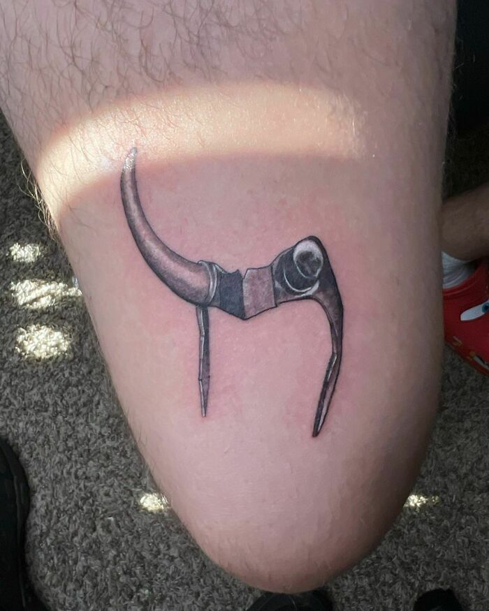 Marvel tattoo of a minimalist Mjolnir design on thigh.