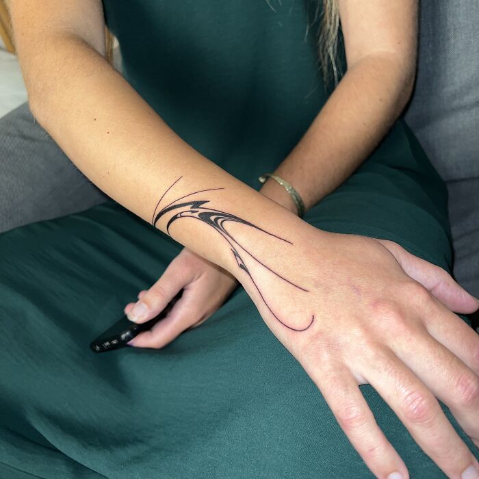 Arm adorned with a flowing tattoo design inspired by traditional Sernakkab marbling art.