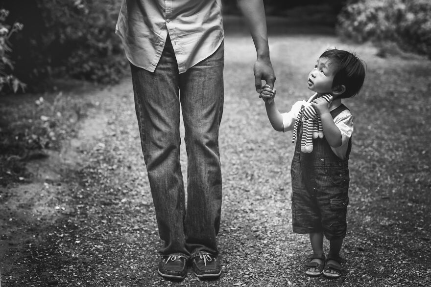 Black and white photograph of a dad holding his son's hand in a park