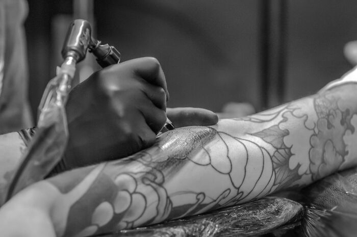 Person Being Tatted By Tattoo Artist