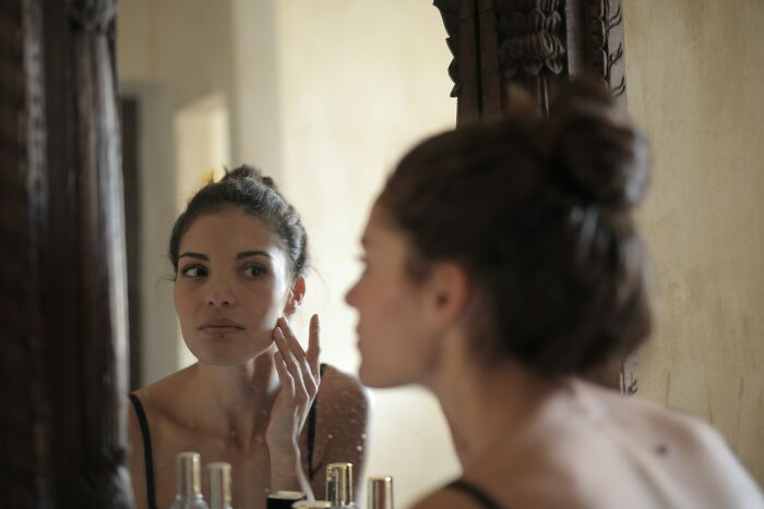 Woman Taking Care Of Her Face In Front Of The Mirror 