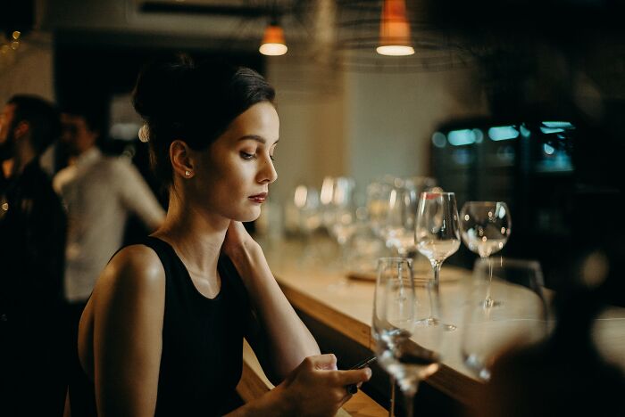 Woman Scrolling On Phone While Drinking Wine 