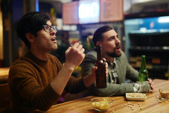 Two Men Looking At Tv And Drinking Beer 
