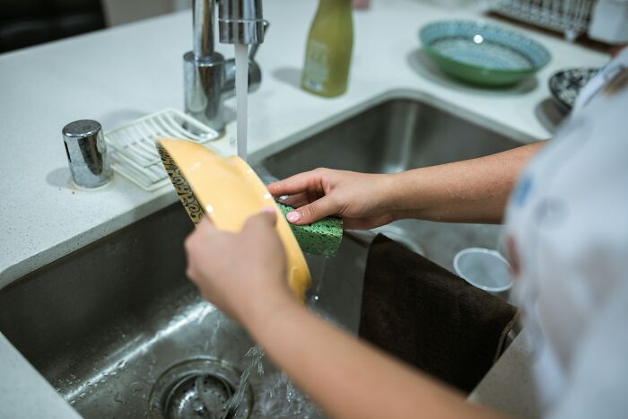Woman Washing Dishes In A Sink 