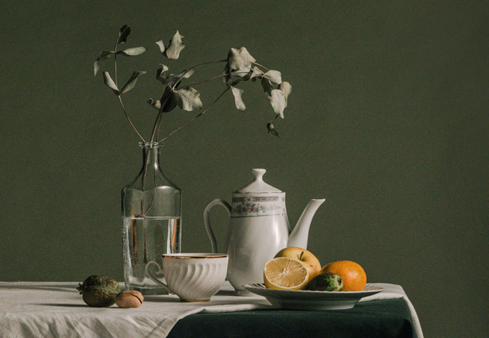 Vase with flower, tea and fruits on table