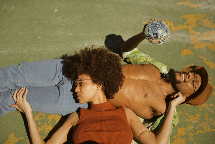 Man and woman lying on the ground and man looking at shiny disco ball