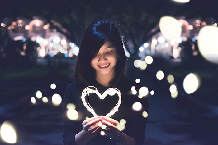 Woman looking of heart shaped fairy lights