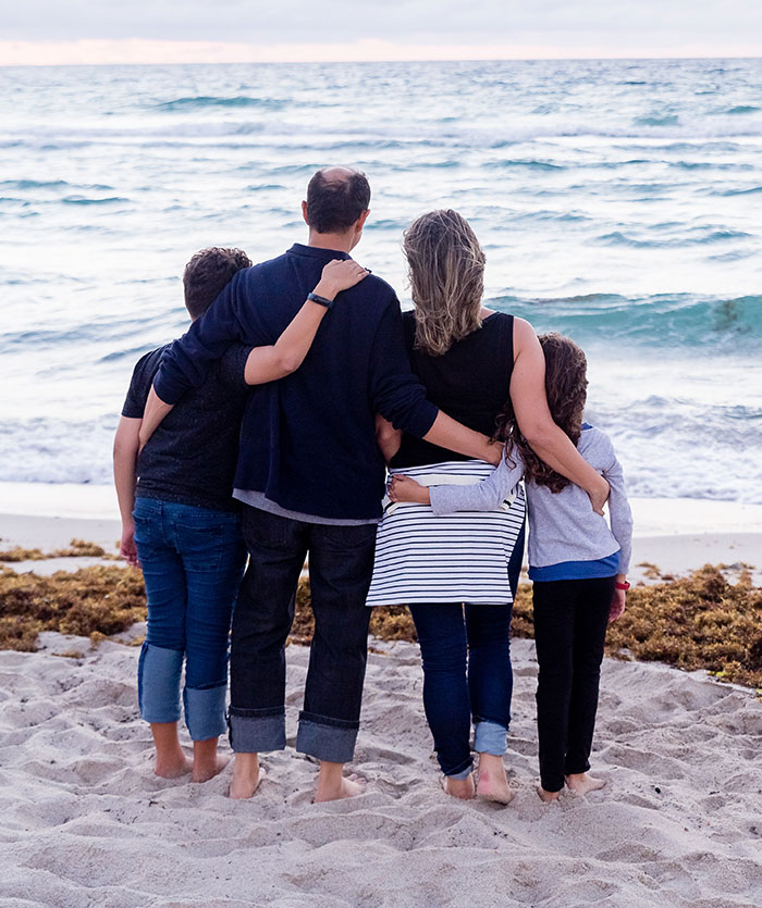 Family hugging and looking at ocean