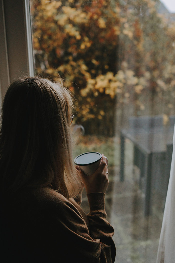 Woman drinking coffee and looking through the window